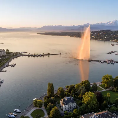 Vue aérienne de la rade de Genève au petit matin, jet d'eau et les deux rives sous une lumière dorée